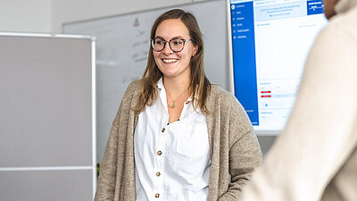 Junge Mitarbeiterin hält eine Präsentation und schaut glücklich nach rechts