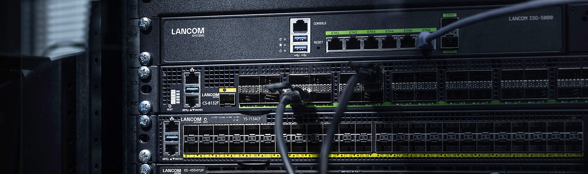 Drei LANCOM Switches eingebaut im Rack mit Kabeln: Core Switch LANCOM CS-8132F, Aggregation Switch LANCOM YS-7154CF und Access Switch LANCOM XS-4554XUP